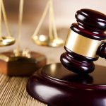 A wooden gavel and scales of justice on a table