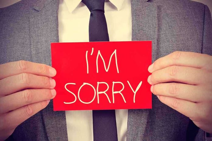 A man in a suit holding a red sign that says IM SORRY