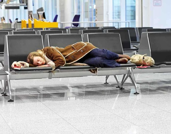 A traveler sleeping on a bench in an airport waiting area