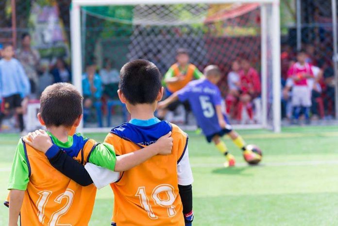 Two boys watching a soccer game together.