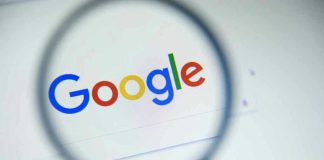 Google logo viewed through a magnifying glass.