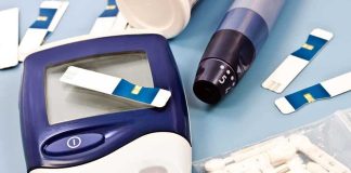 Blood glucose monitor with testing strips and a lancing device on a blue background