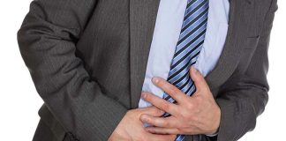 Man clutching stomach in pain, wearing a suit.