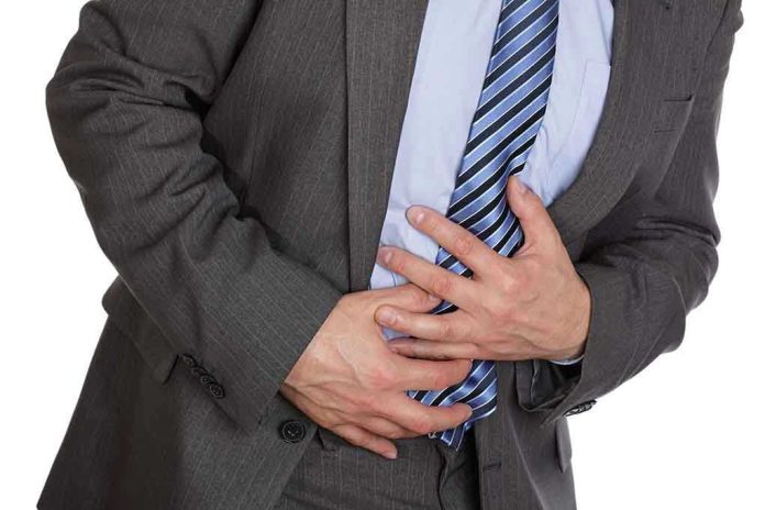 Man clutching stomach in pain, wearing a suit.