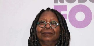 Person with dreadlocks and round glasses, smiling slightly.