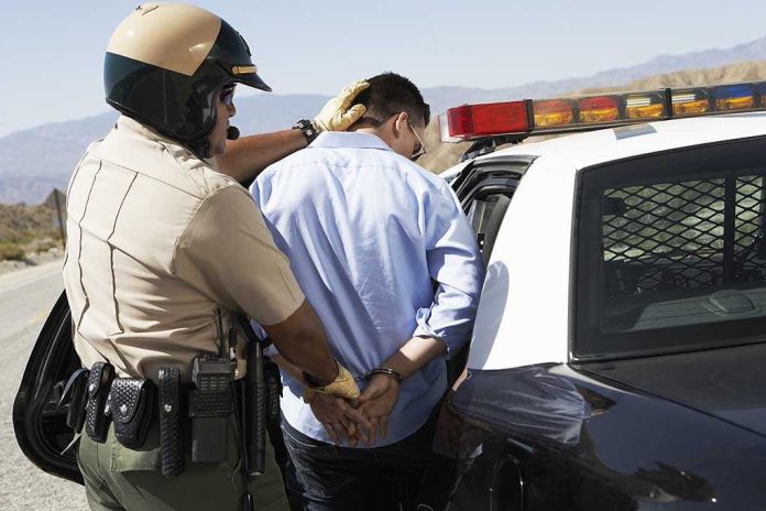 Police officer arresting a suspect near a patrol car