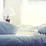 A cozy unmade bed with soft pillows and bedding in a well-lit room