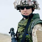 A soldier in camouflage uniform wearing sunglasses and tactical gear