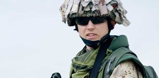 A soldier in camouflage uniform wearing sunglasses and tactical gear