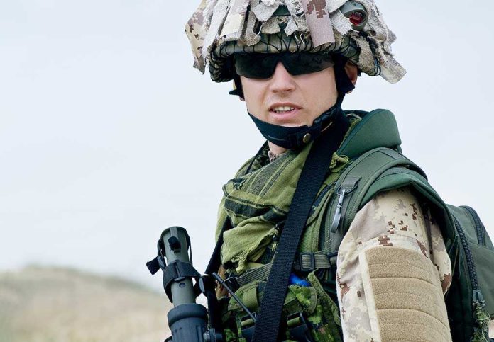 A soldier in camouflage uniform wearing sunglasses and tactical gear