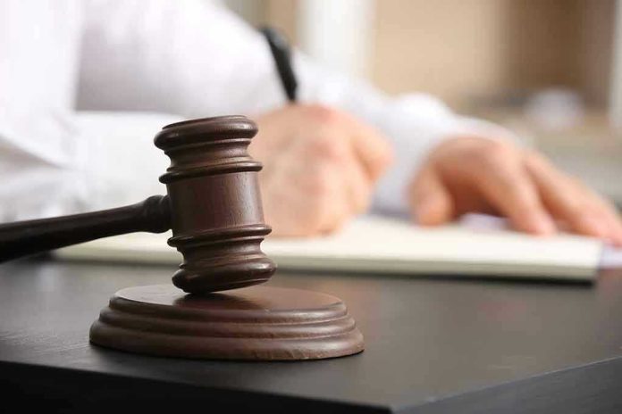 Judges gavel on desk with person writing.