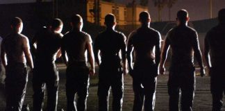 Silhouettes of uniformed individuals standing in formation at night