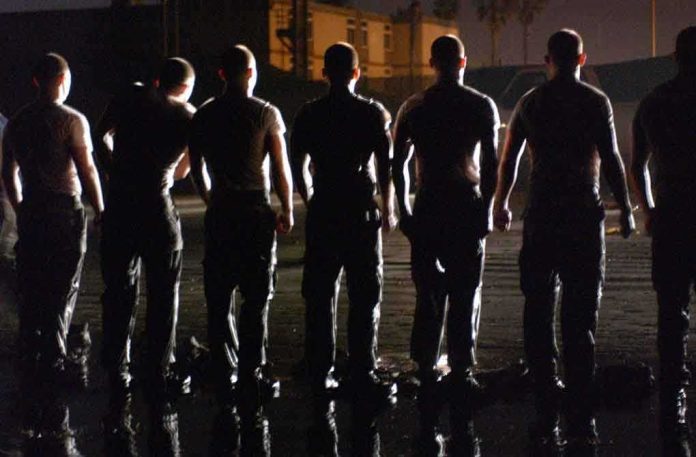Silhouettes of uniformed individuals standing in formation at night