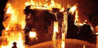 A firefighter battling a large house fire at night