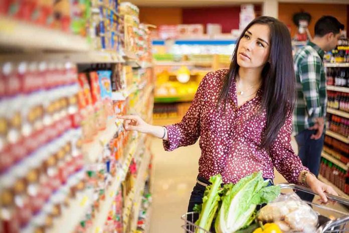 Woman shopping in a grocery store aisle with a cart full of vegetables