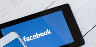 Smartphone and tablet displaying the Facebook logo on a wooden surface