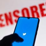 Phone displaying Twitter app with CENSORED in background.
