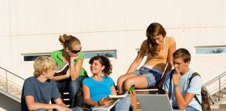 Group of students sitting on a bench outdoors, engaged in study and discussion