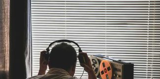 Person wearing headphones listening to a reel-to-reel tape recorder