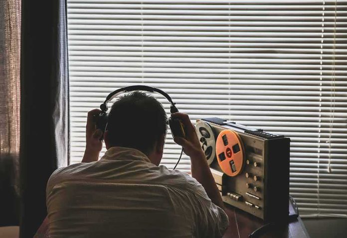 Person wearing headphones listening to a reel-to-reel tape recorder