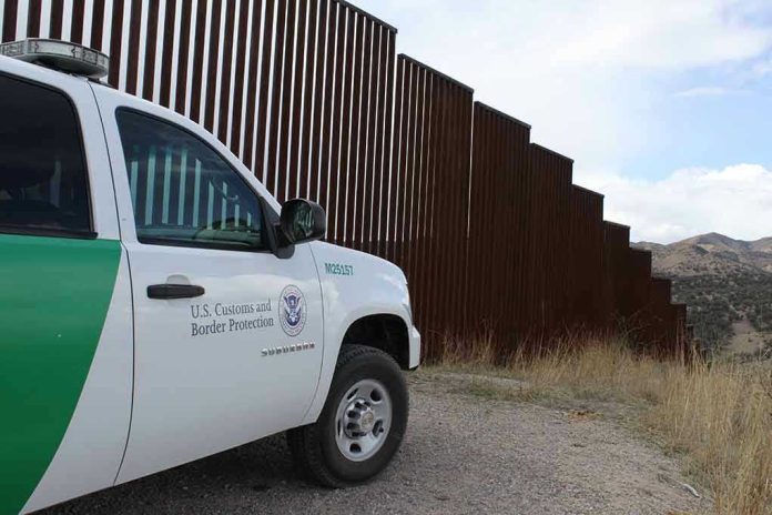 1478048393 Border protection vehicle near a large metal fence.
