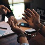 Forced Abortion Horror: Identity Fraud in Play Person handcuffed in discussion with another person