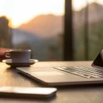 SHOCKING Gut-Brain Link — Coffee Does WHAT? Laptop, coffee cup, and phone on wooden table.