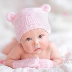 Actress Defies Law Using Dead Son’s Sperm A cute baby wearing a pink knitted hat and mittens, lying on a soft surface