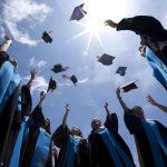 Google’s Former CEO Eric Schmidt BOOED for AI Speech Graduating students celebrating by throwing their caps into the air under a bright blue sky
