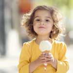 Childhood Snacks Trigger Lasting Brain Changes! A young child with curly hair holding an ice cream cone outdoors