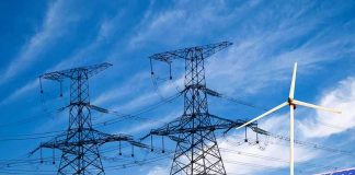 Energy Giants Merge — Will It Mean Bigger Bills? Solar panels and a wind turbine with power lines against a blue sky