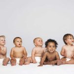 Future Crisis: Population Plunge Threatens Nations Five diverse babies sitting on a neutral background, displaying playful expressions