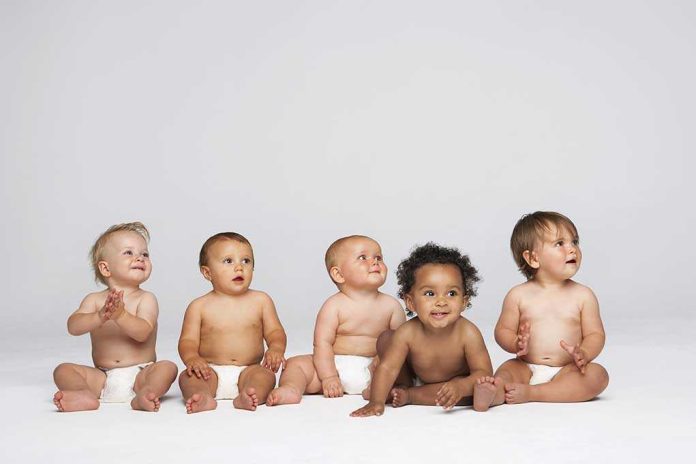 shutterstock_144900970 Five diverse babies sitting on a neutral background, displaying playful expressions