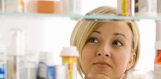 Menstrual Pay Fight Explodes — What’s Next? A woman thoughtfully looking at a medicine cabinet filled with various medications