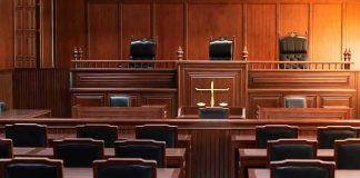 Espionage Bombshell: Former Advisor Flips Empty courtroom with wooden furniture and black chairs.