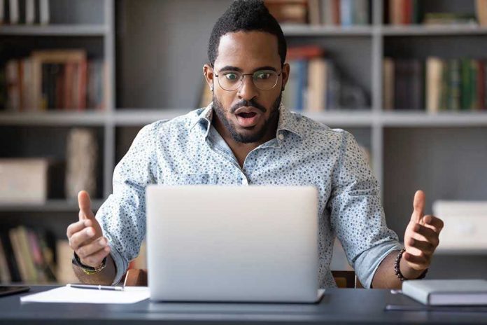 Man surprised while looking at laptop screen.