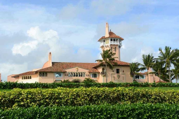 Large pink mansion with tower, palm trees, and garden.