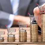 Inflation Spike Shocks: Three-Year High Mini shopping carts on stacks of coins, business background.