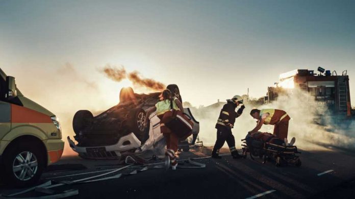 Emergency responders at an overturned, smoking car on a roadway