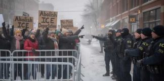 Protesters holding signs against ICE in a snowy environment
