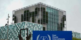 Arrest Showdown: Netanyahu Dares New York International Criminal Court building with sign in foreground.