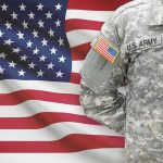 Army Captain’s Chilling Abortion Plot Exposed Soldier in camouflage uniform standing before American flag.