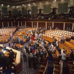 Legislative chamber with members gathering on the floor