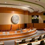 Interior view of a government chamber with wooden paneling and seating