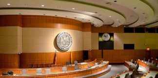 Trump’s AI Gambit Rattles Contractors Interior view of a government chamber with wooden paneling and seating