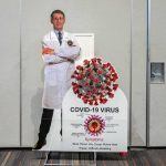 Cardboard cutout of doctor with COVID-19 virus info display