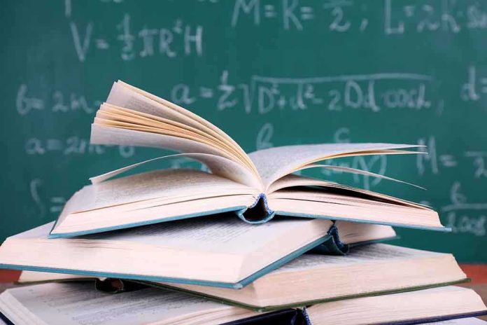 A stack of books with one open on top, in front of a chalkboard filled with mathematical equations