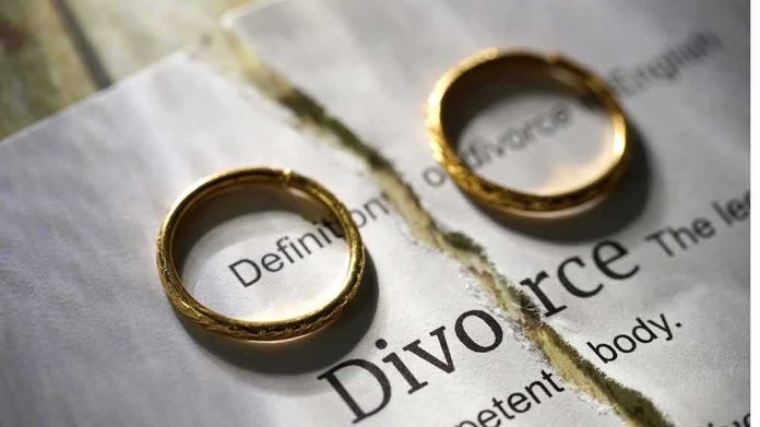 Two wedding rings placed on a torn page with the word 'Divorce'