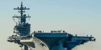 Navy’s $12B Data Engine Gets One Boss Aircraft carrier guided by tugboats in a harbor