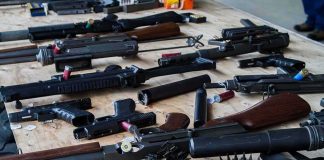 DOJ Busts Border Gun Highway Assorted firearms and ammunition laid out on a wooden table